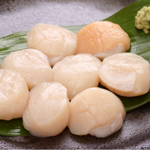 Several peeled scallops arranged on a green leaf with a small dollop of sauce in the upper right, photographed on a gray speckled surface. - Japanese Hokkaido Scallops (1kg | Large | Sashimi Grade For Cooking)