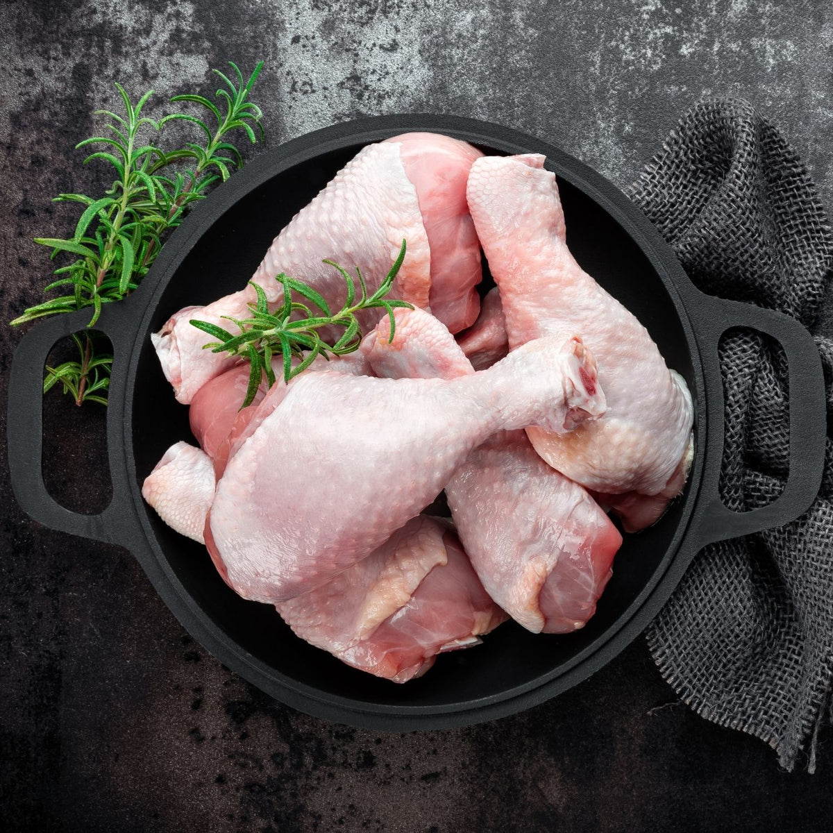 Raw chicken drumsticks in a black cast iron skillet with rosemary on a dark surface - Australian Hormone Free Chicken Drumsticks (400g)