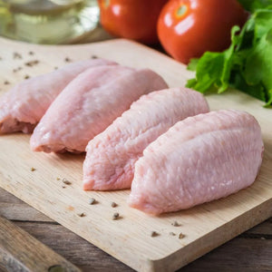 Raw chicken wings on a wooden cutting board with tomatoes and lettuce in the background - Australian Hormone Free Chicken Mid Wings (400g)