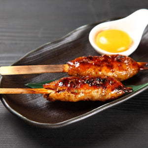 Two skewered grilled chicken thigh mince on a dark plate with a small bowl of dipping sauce. - 澳洲無激素免治雞髀肉(400克)