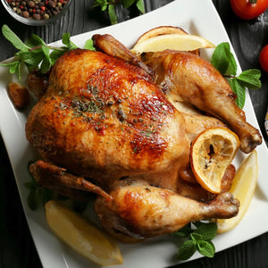 Roasted chicken with lemon wedges on a white plate with herbs. - 澳洲無激素全雞(1.6公斤)|買三送一