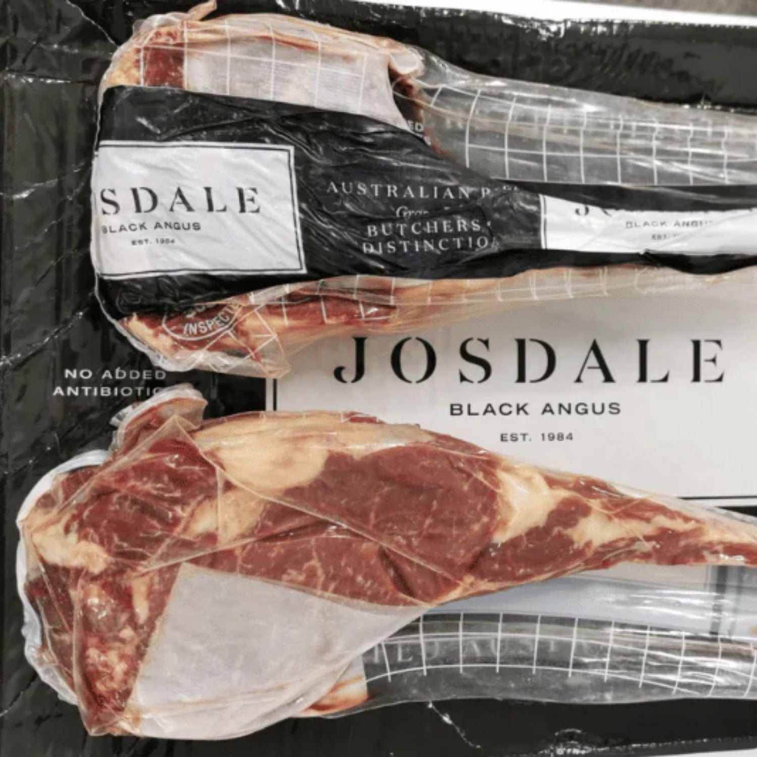 Packaged Josdale Black Angus tomahawk steak with visible branding on a black background - 澳洲優質黑安格斯斧頭扒