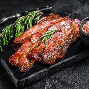 Bacon slices on a black slate board with rosemary and salt. - 荷蘭煙燻五花腩煙肉(200克)