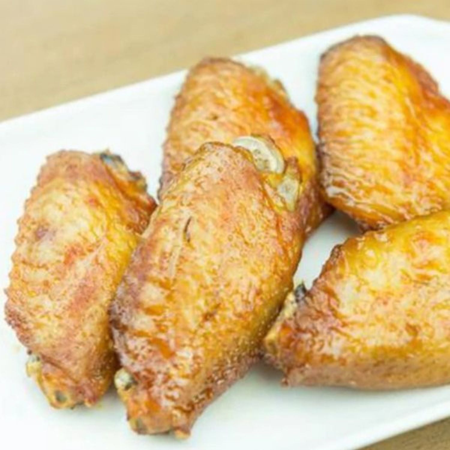 Baked chicken wings on a white plate with a beige background - EU Hormone Free Chicken Mid-Wings (908g)