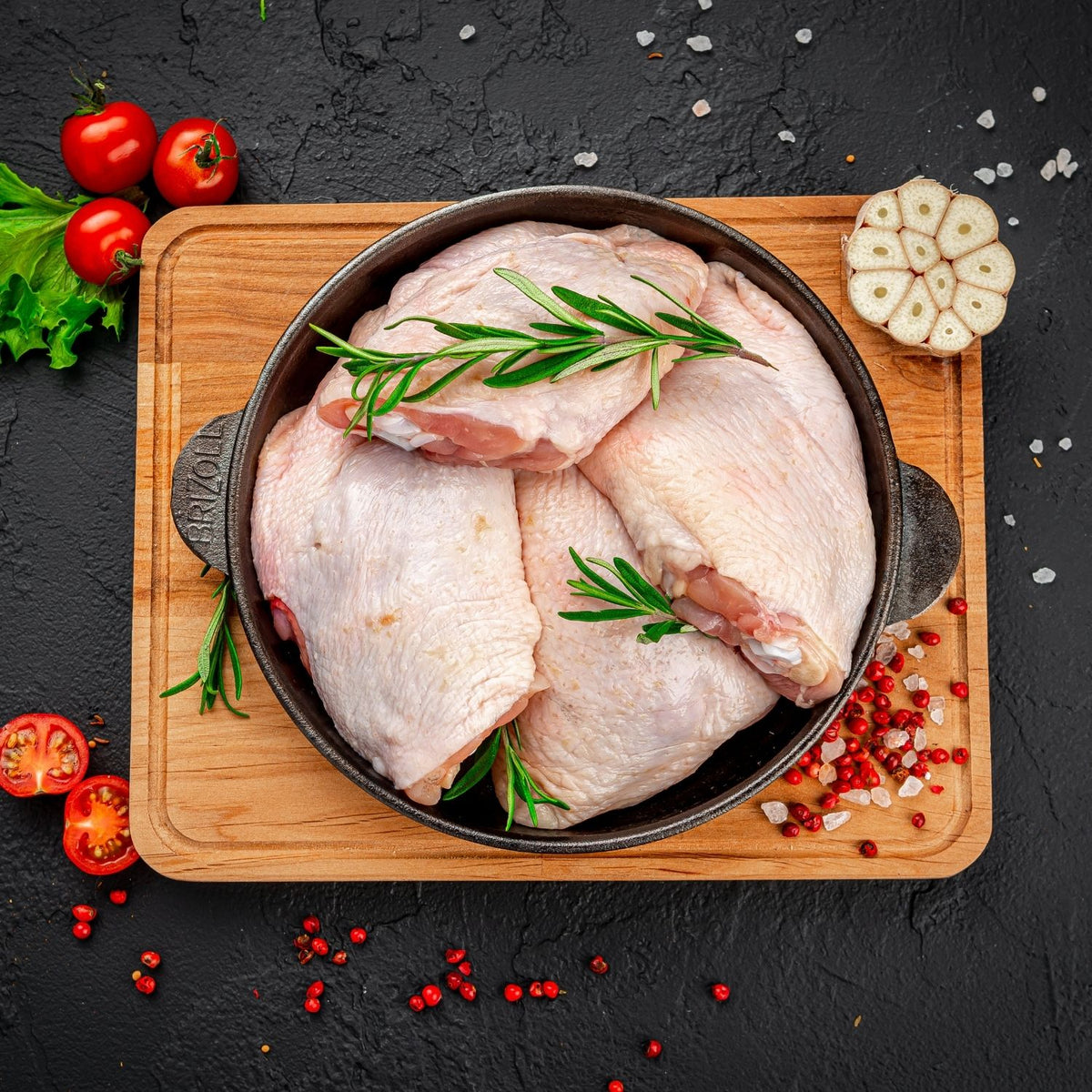 Raw chicken thighs in a pan on a wooden cutting board with herbs and spices on a dark surface. - EU Hormone Free Chicken Thighs Skin-On with Back Bone (908g)