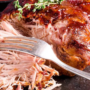 Shredded pulled pork with a fork and a partially eaten pork roast on a dark surface. - 歐盟無激素梅花肉(肩膀)(2公斤)|九五折