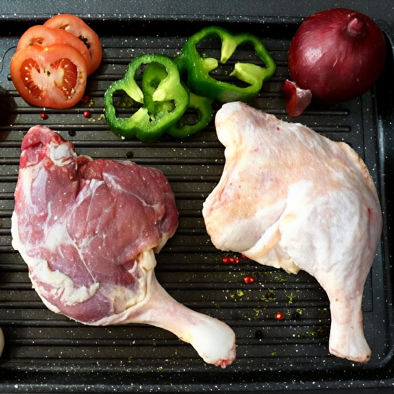 Raw duck legs, green bell peppers, tomatoes, and a red onion on a grill pan. - 無激素法國連皮鴨髀