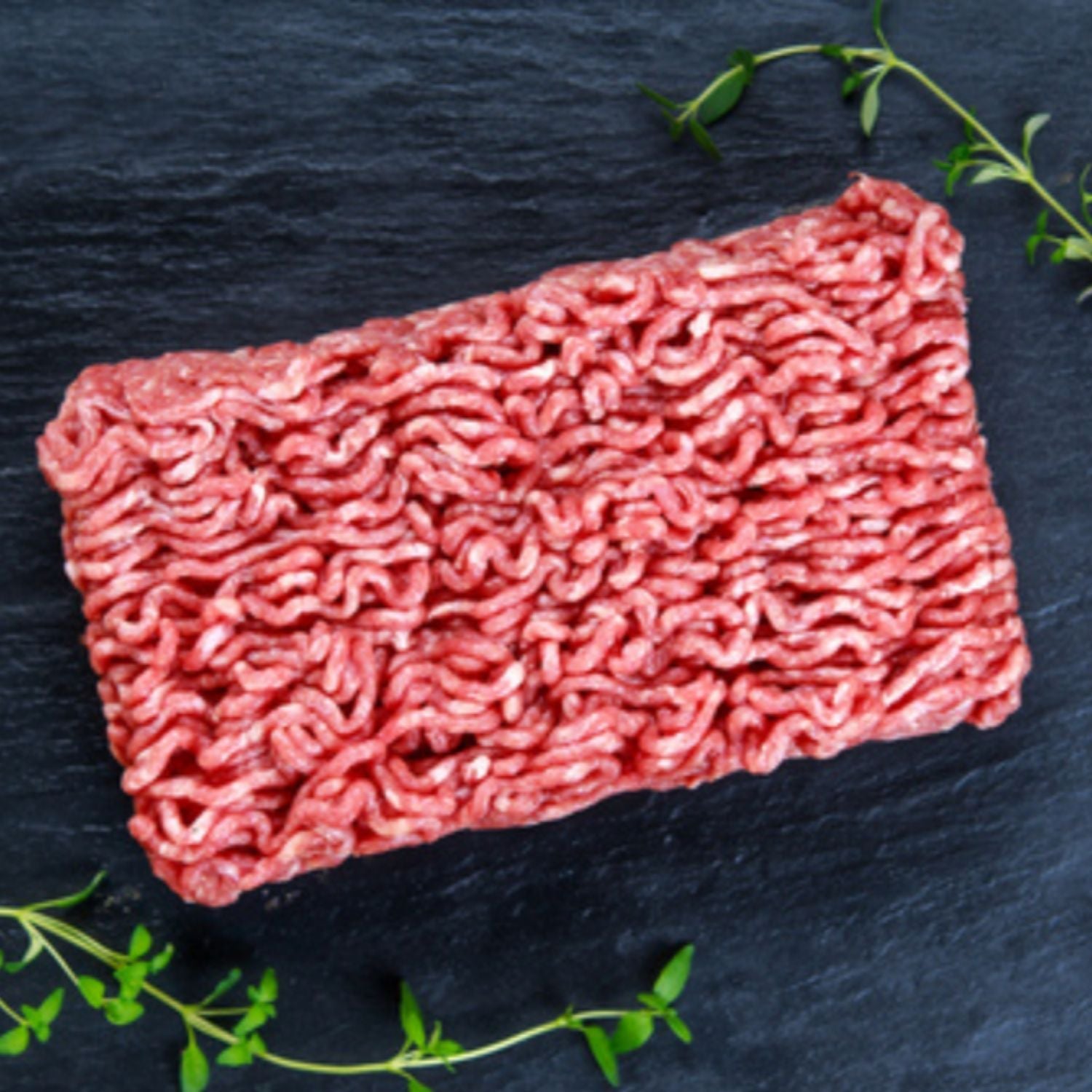 Raw ground beef on a dark slate surface with fresh herbs - 紐西蘭優質草飼瘦免治牛肉（〜85％VL，500克）