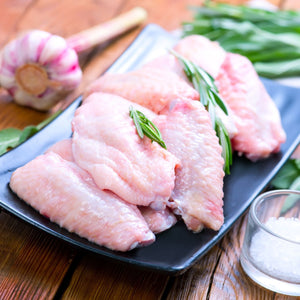 Raw chicken wings on a black plate with green herbs on a wooden surface - 批發價澳洲無激素雞中翼(400克)|買二十送六
