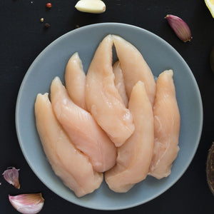 Raw chicken breast tenderloins on a gray plate with garlic cloves on a dark surface - Wholesale Australian Hormone Free Chicken Tenderloins (400g) | Buy 20 Get 6 Free