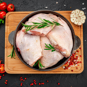 Raw chicken thighs in a pan on a wooden cutting board with herbs and spices. - 澳洲無激素連皮雞扒(400克)|買二十送六