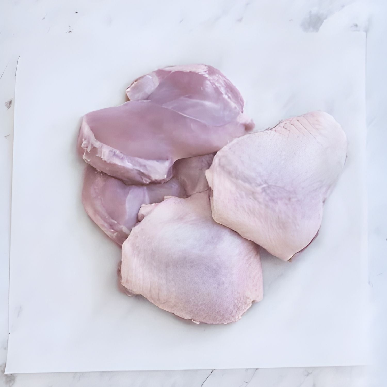 Raw chicken thighs on a white marble surface - 澳洲無激素連皮雞扒(400克)|買二十送六