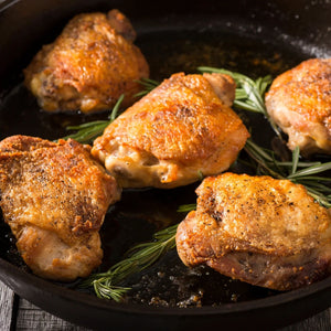 Roasted chicken thighs with rosemary in a black skillet on a wooden surface - 澳洲無激素連皮雞扒(400克)|買二十送六